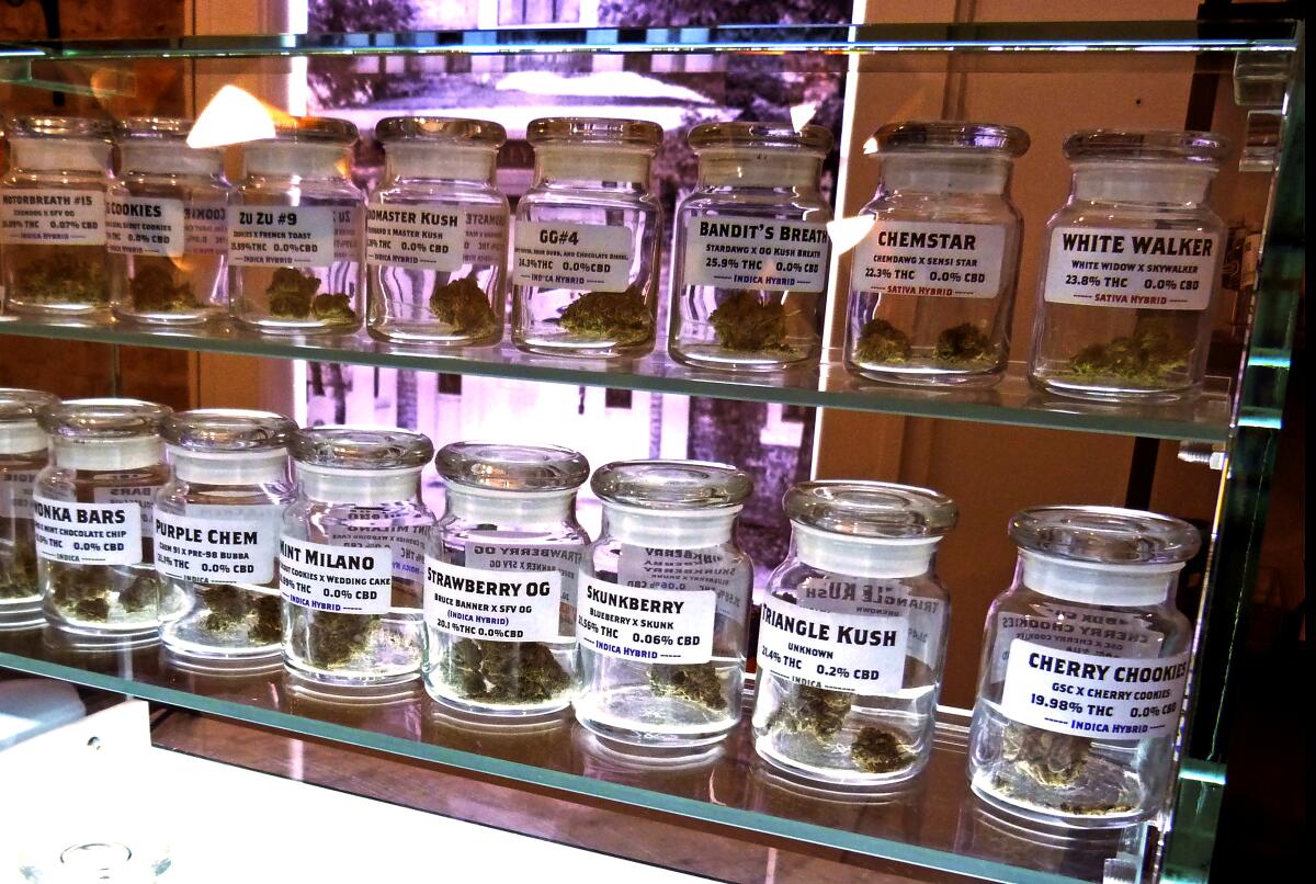 Strains of marijuana in rows of small glass jars on display at Arbors Wellness