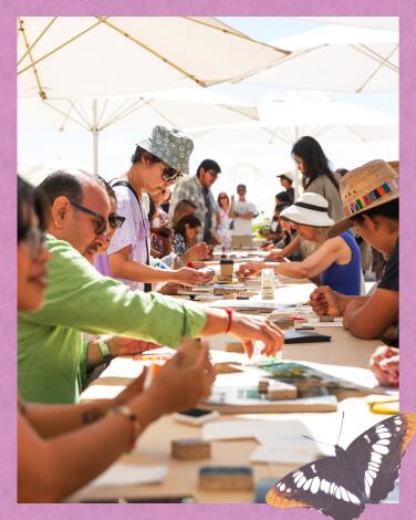 People sit at a long table and work on crafts 