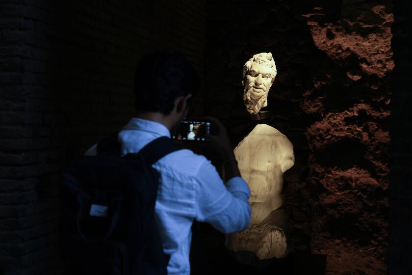 A visitor takes a picture to a statue of Pan during the press preview of the newly-restored Domus Tiberiana, one of the main imperial palaces on Rome's Palatine Hill, in Rome, Italy, Wednesday, Sept. 20, 2023. The Domus Tiberiana will reopen to the public on Sept. 21. (AP Photo/Gregorio Borgia)
