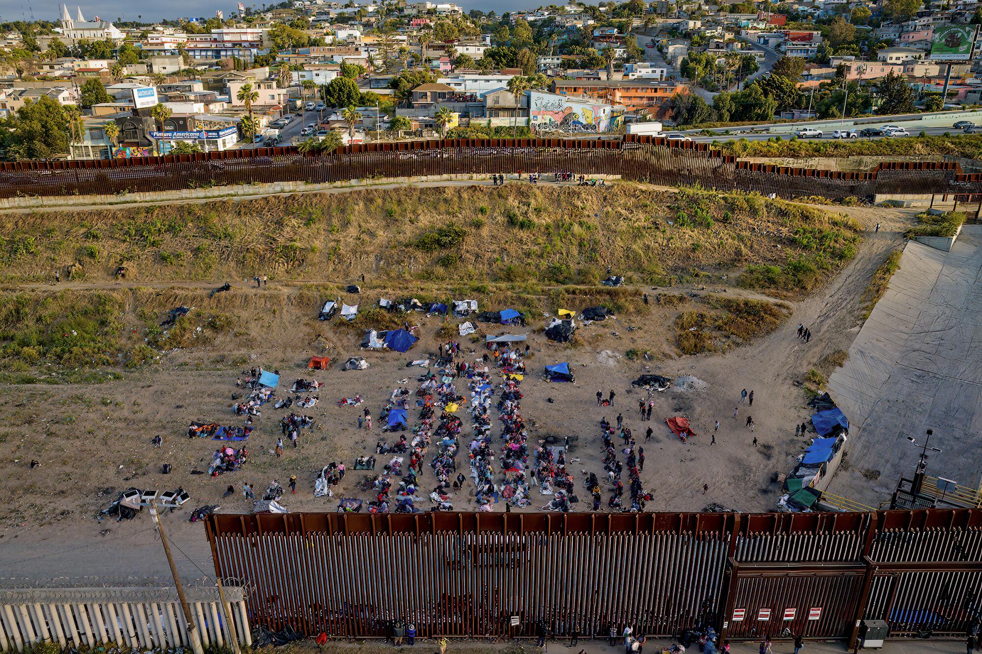 More than 200 migrants wait at the border fence for the end of Title 42 in San Diego on Thursday.