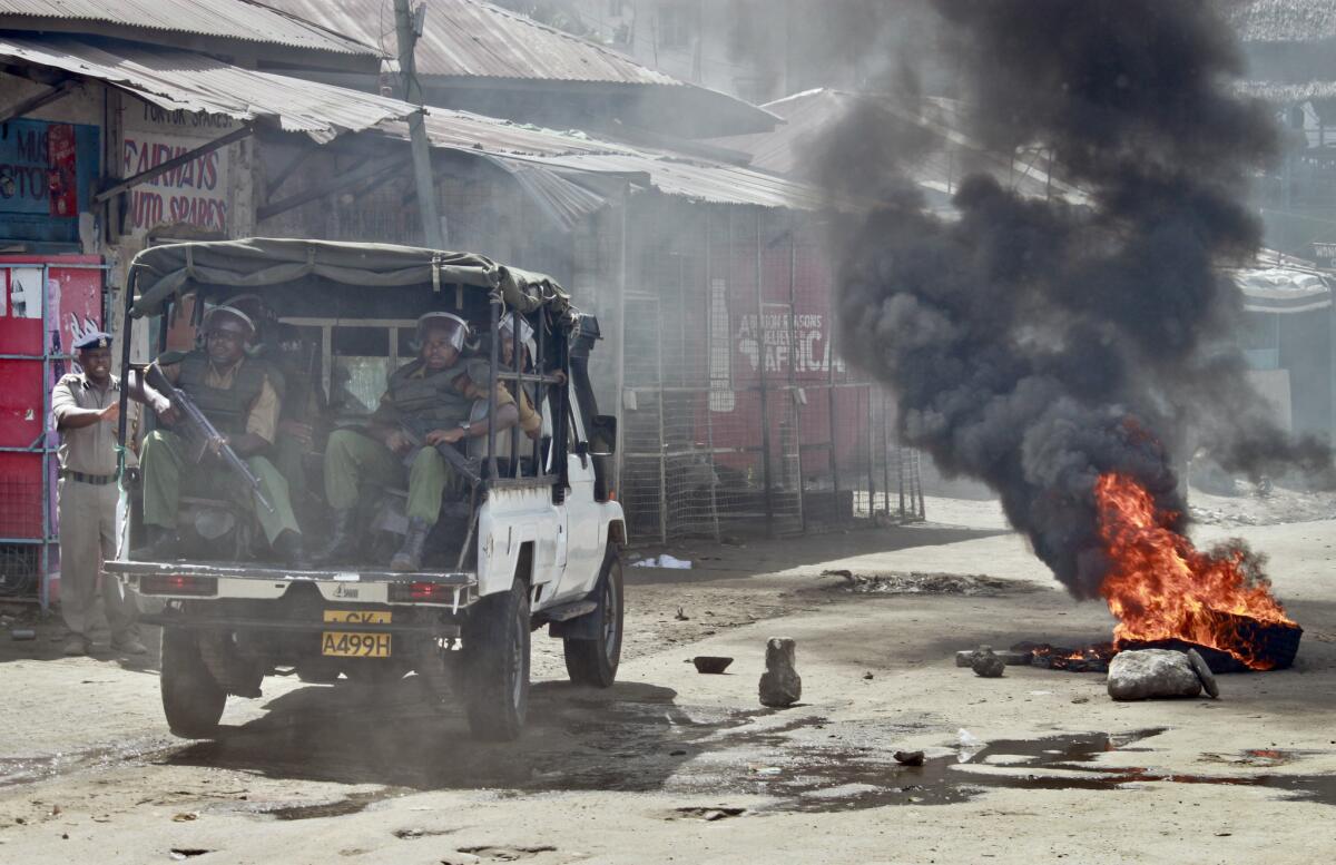 Kenyan security forces patrol past a burning tire following rioting in Mombasa on Friday.