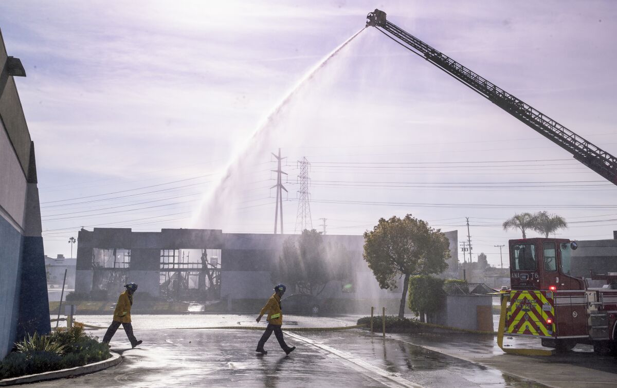 Firefighters walk past a burned-out building