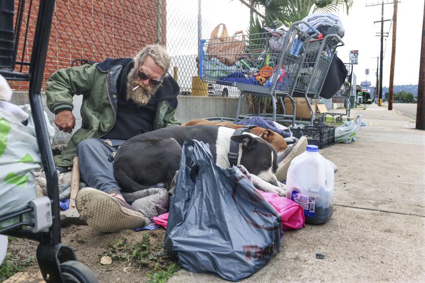 Jacob(last name not given) sits with his Two Pitbulls Buddy and Red along Johnson Avenue on Thursday, January 13, 2022 in El Cajon.(Photo by Sandy Huffaker for The San Diego Union-Tribune)