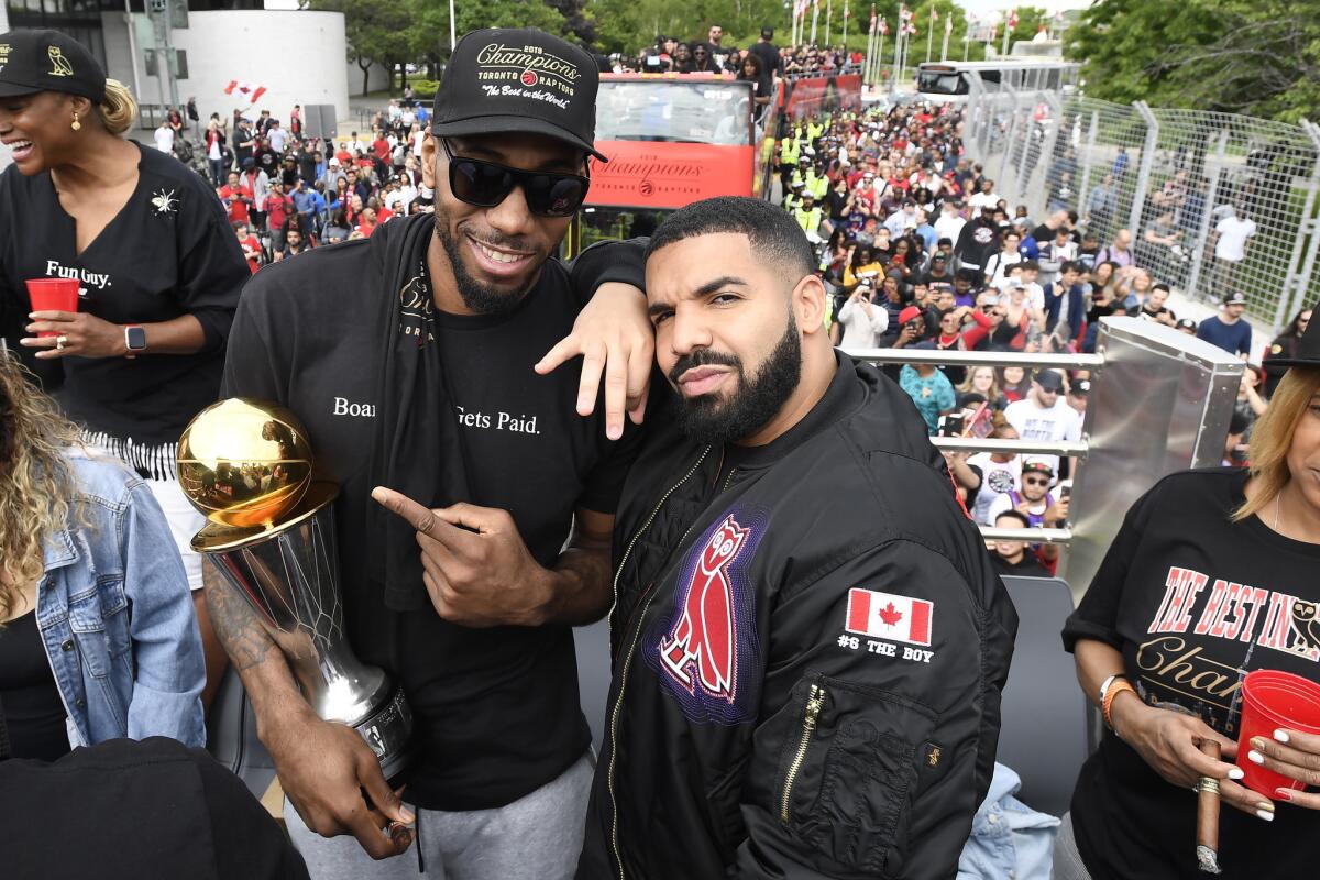 Toronto Raptors forward Kawhi Leonard poses with his NBA Finals MVP trophy and rapper Drake.