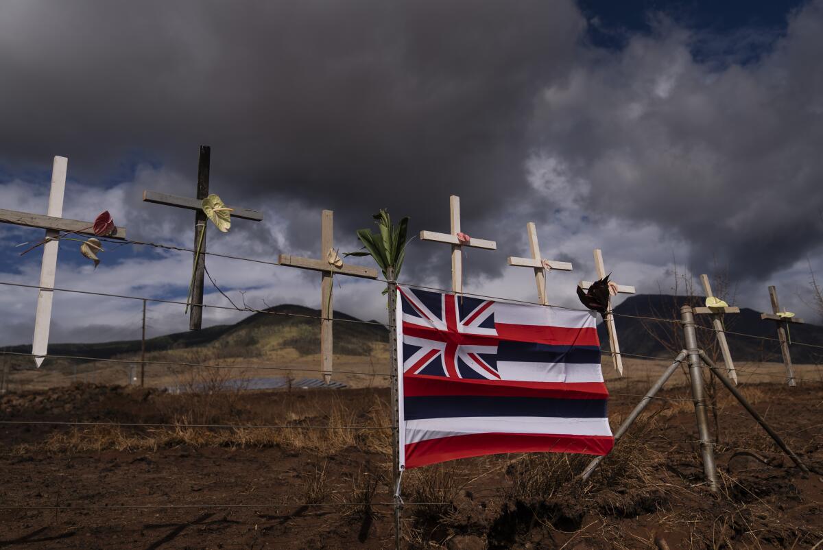 A Hawaiian flag and crosses honoring wildfire victims can be seen in Lahaina on the Hawaiian island of Maui on Aug. 21.