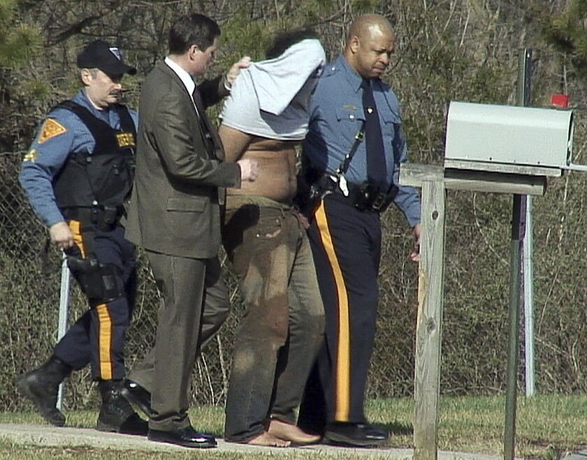 FILE - Francisco Herrera-Genao, of New Brunswick, N.J., second from right, is seen wearing shirt over his head after being captured, as he is led to the New Jersey State Police barracks in Somerville, N.J., April 6, 2007. Herrera-Genao, serving a 117-year prison sentence for a botched bank heist that led to the accidental death of an FBI agent, could be free in as soon as 2026, thanks to legislation signed by former President Donald Trump. (Loren Fisher/The Courier-News via AP, File)