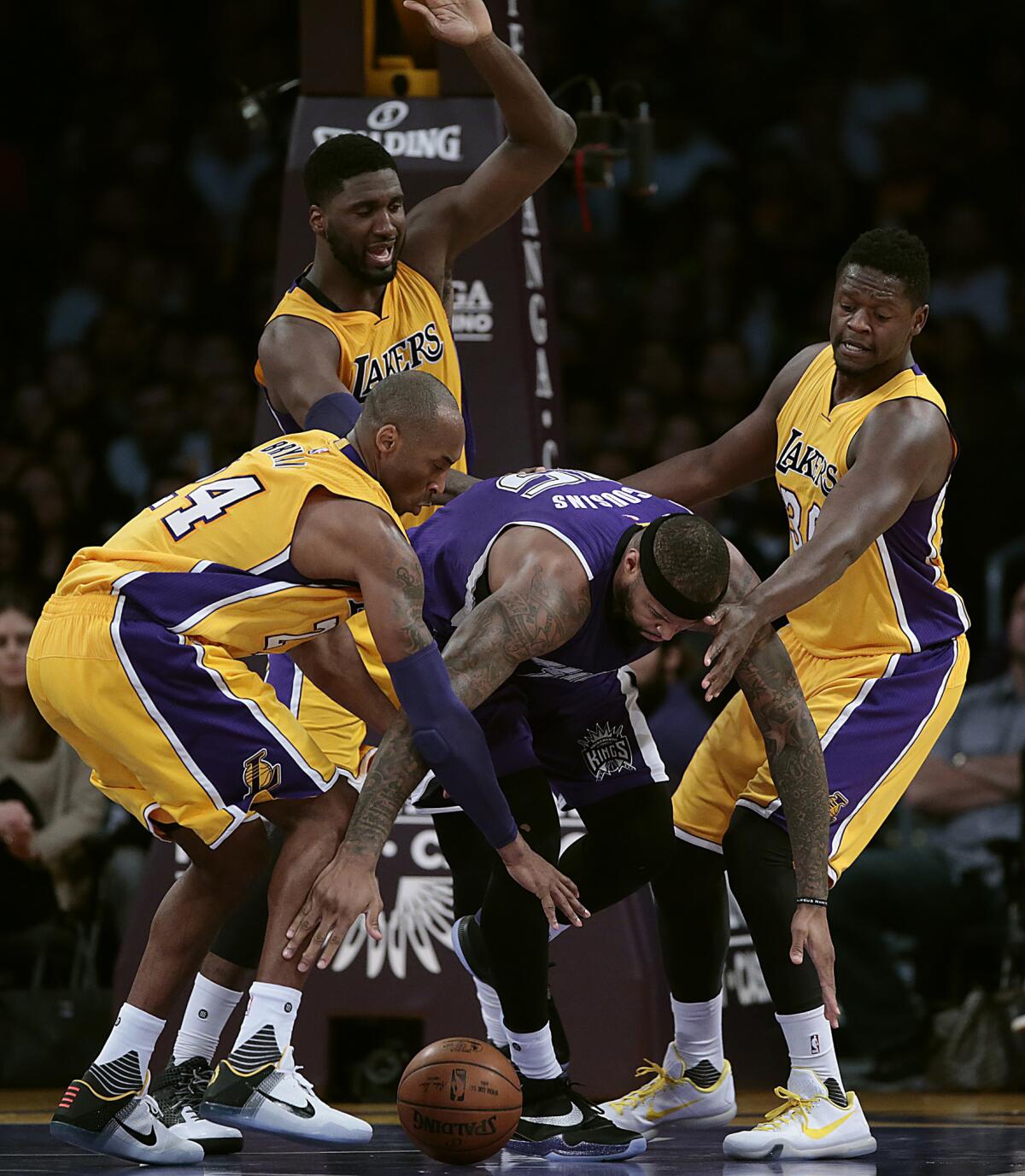 Sacramento center DeMarcus Cousins is swarmed by Lakers Kobe Bryant, left, Roy Hibbert and Julius Randle during the first half at Staples Center.
