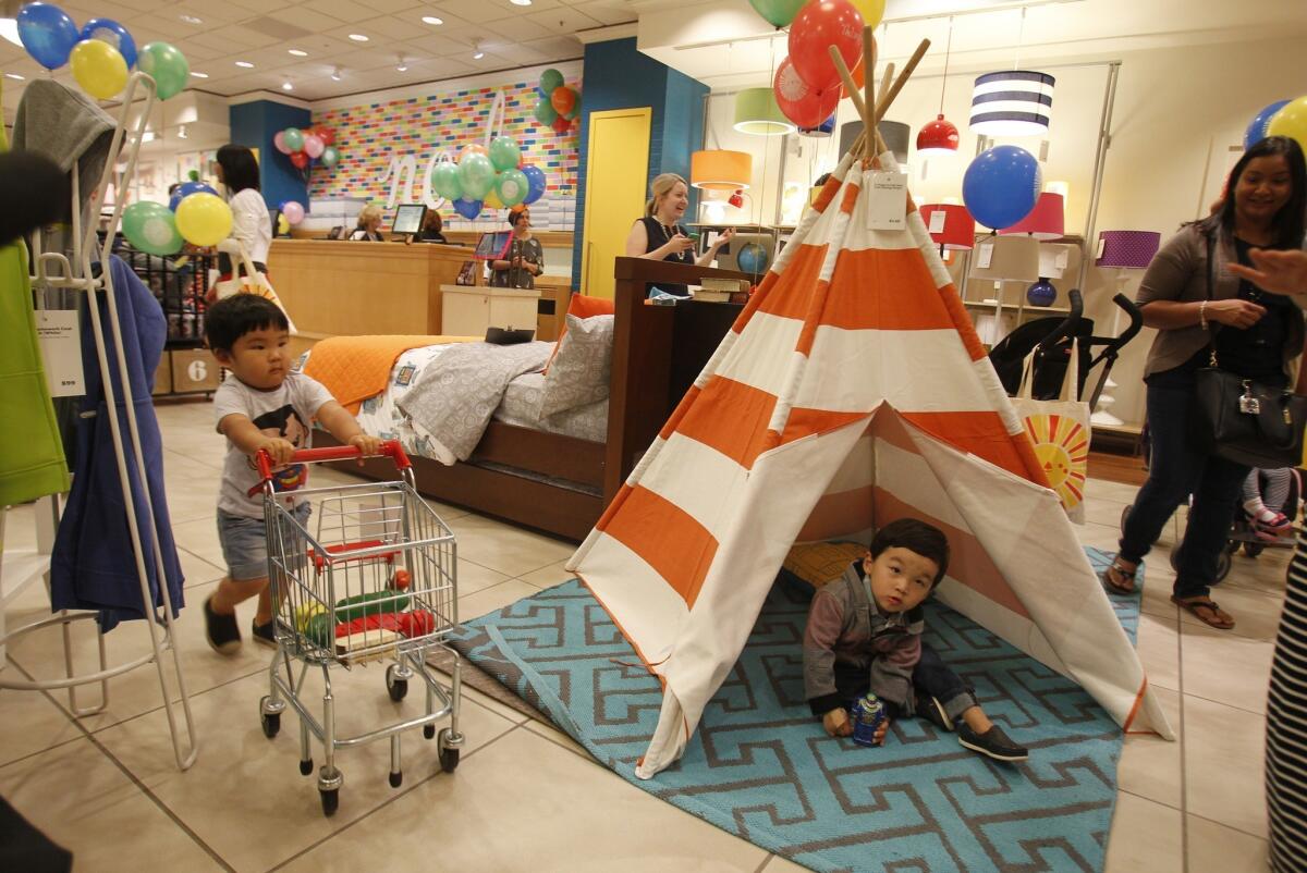 Shopper in training: Oliver Hong, left, 1, of Aliso Viejo, exhibits excellent command of his miniature cart ($69) while Owen Lee, 2, of Irvine, plays in the wood and canvas teepee ($149) in the new Land of Nod store in Costa Mesa. The blue Locking Blocks cotton rug comes in sizes ranging from 4-by-6-feet to 8-by-10-feet, $99 to $299.