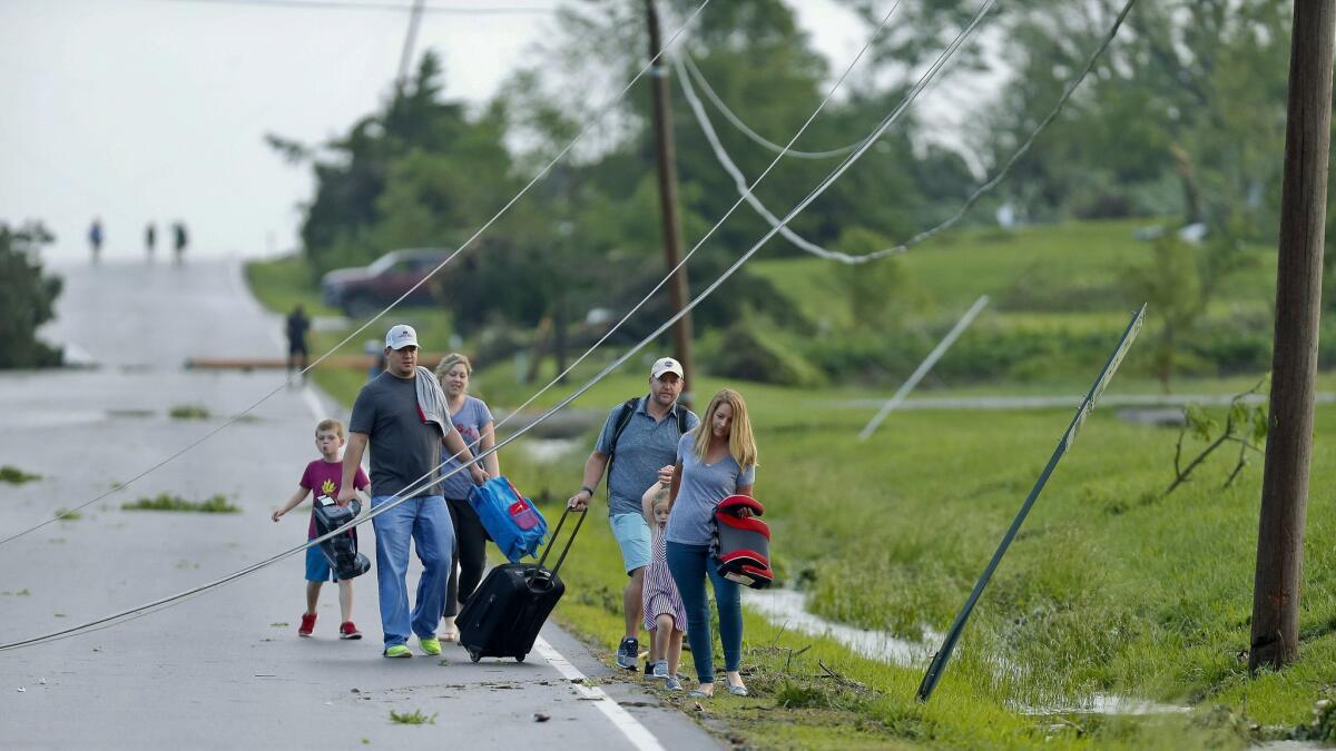 A family ducks under power lines as it makes its way out of a tornado-damaged neighborhood near Lawrence, Kan.