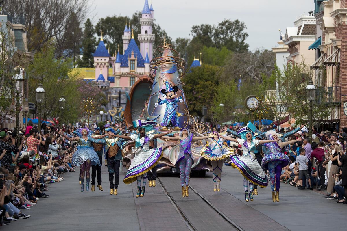 Dancers perform in front of Mickey Mouse on a parade float at Disneyland.