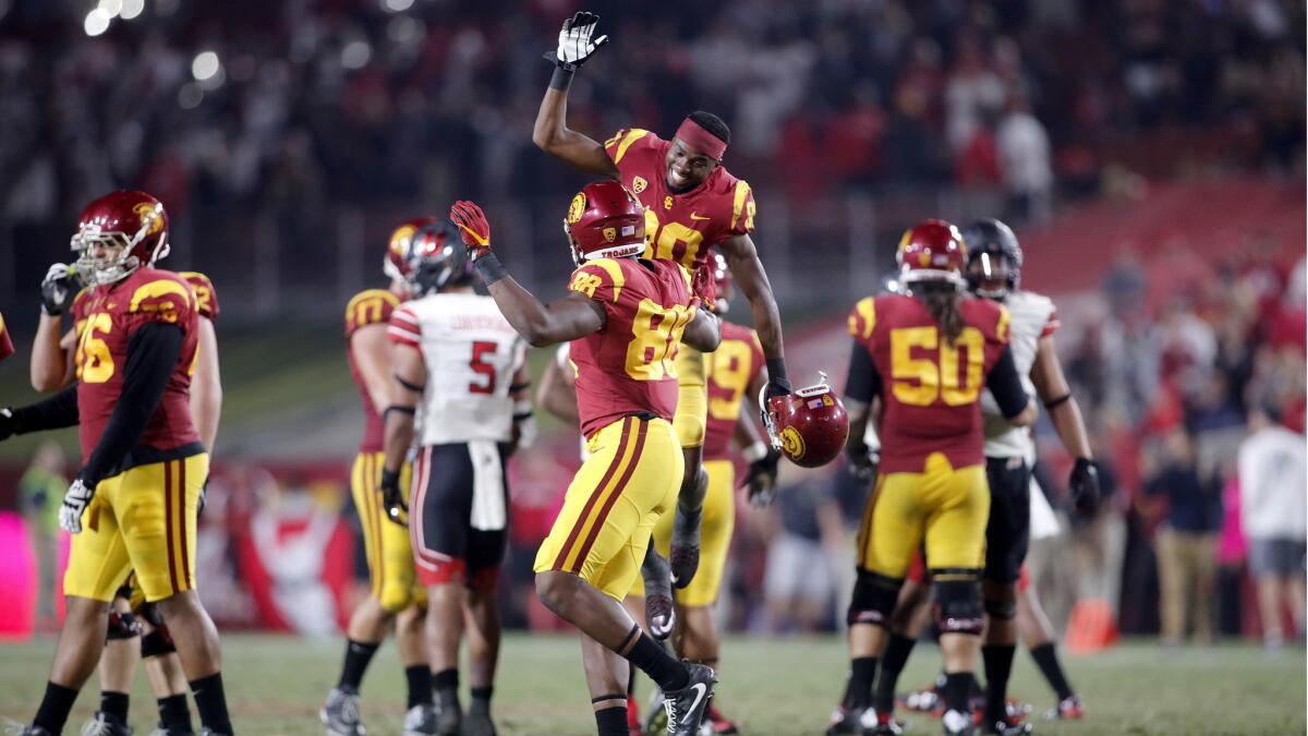 USC's Deontay Burnett leaps in the air while celebrating with Daniel Imatorbhebhe after USC beat Utah 28-27 on Saturday at the Coliseum.