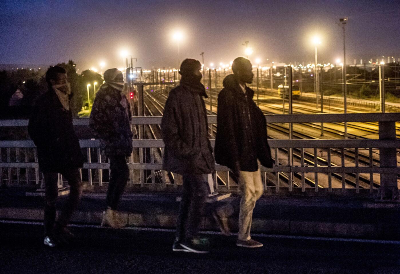 Migrants cross a bridge over the railway tracks of the Eurotunnel terminal on July 28, 2015 in Calais, France.