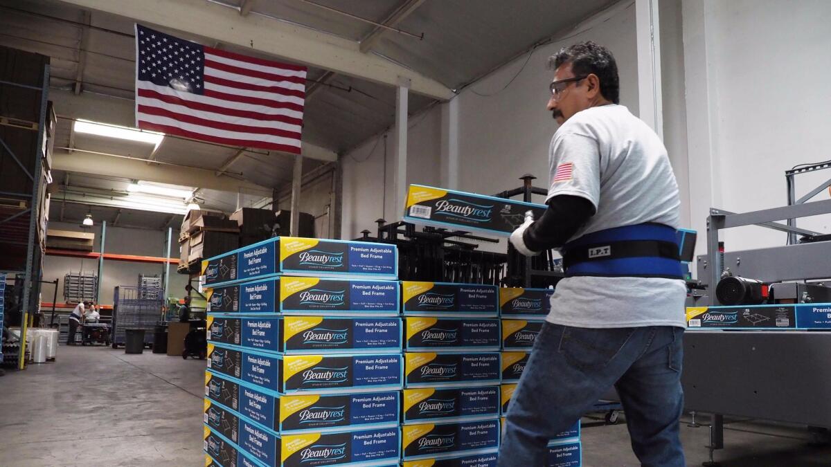 A worker stacks packaged Beautyrest bed frames at the Hollywood Bed Frame Company factory in Commerce in April.