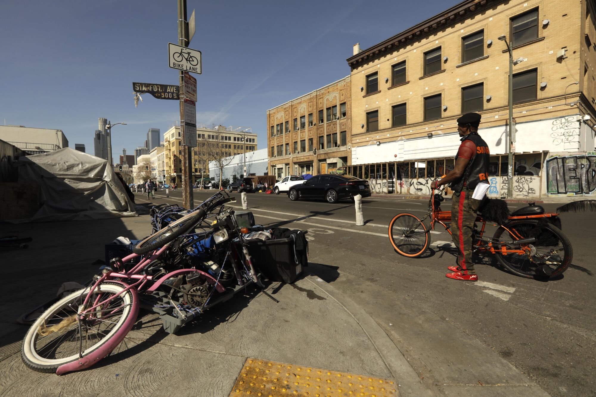 A man on a bicycle next to a pile of bikes on a street corner