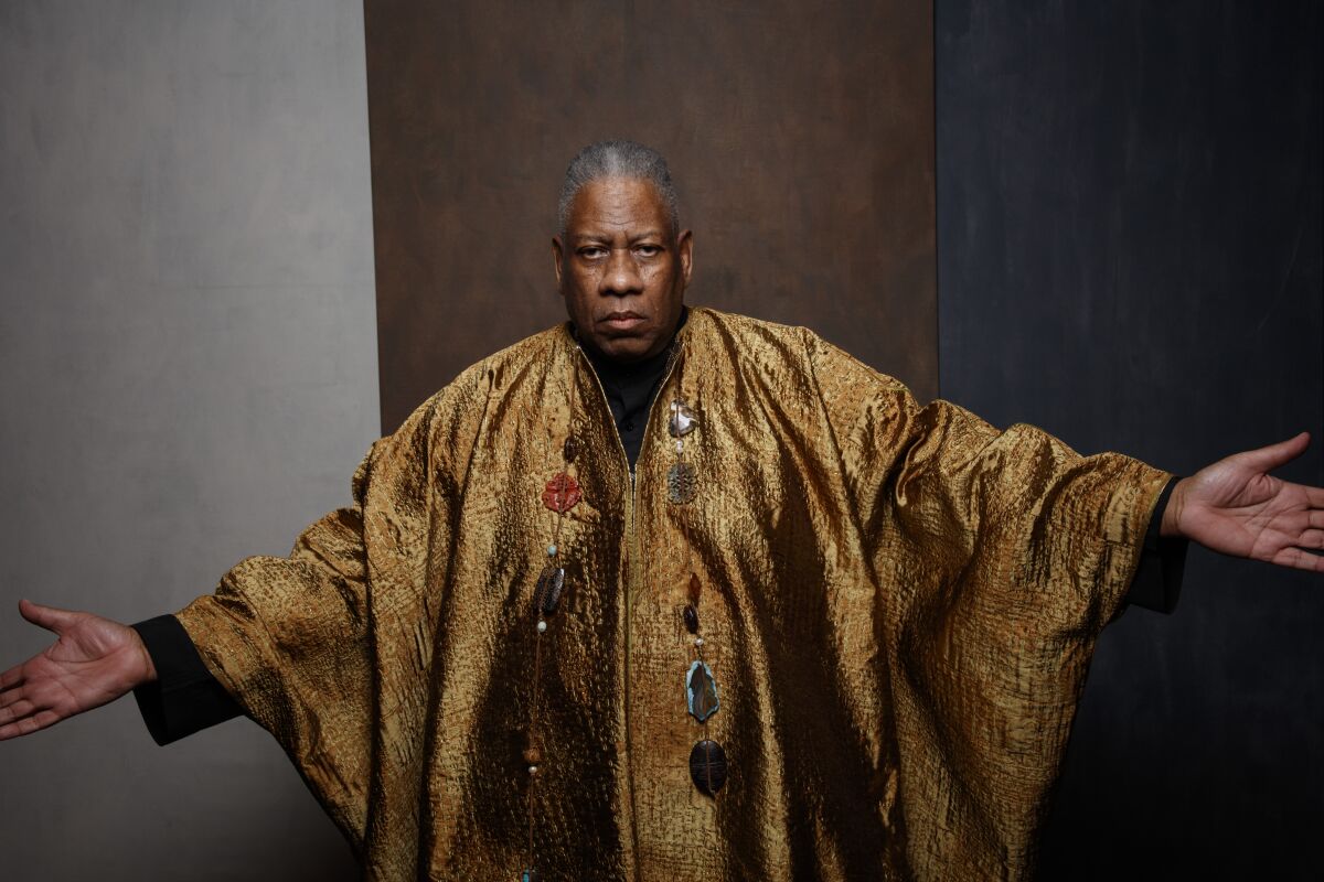 André Leon Talley, in a gold caftan, is seen extending his arms in a formal photo portrait.