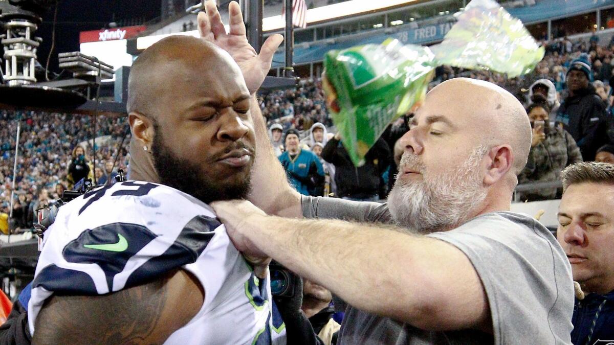 A Seattle Seahawks staff member tries to escort defensive tackle Quinton Jefferson from the field as an object thrown from the stands hits them during the closing moments of the game against the Jaguars on Sunday.