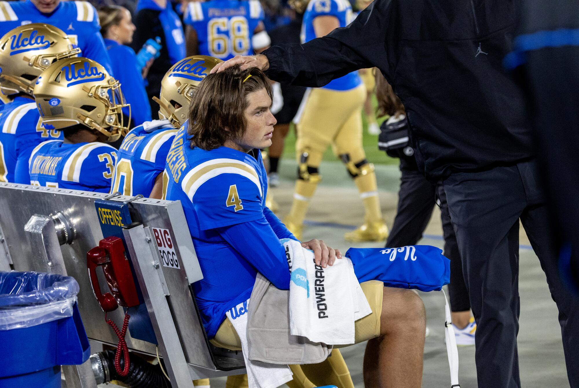 UCLA quarterback Ethan Garbers sits on the bench with a towel on his arm after he was knocked out of the game by Cal