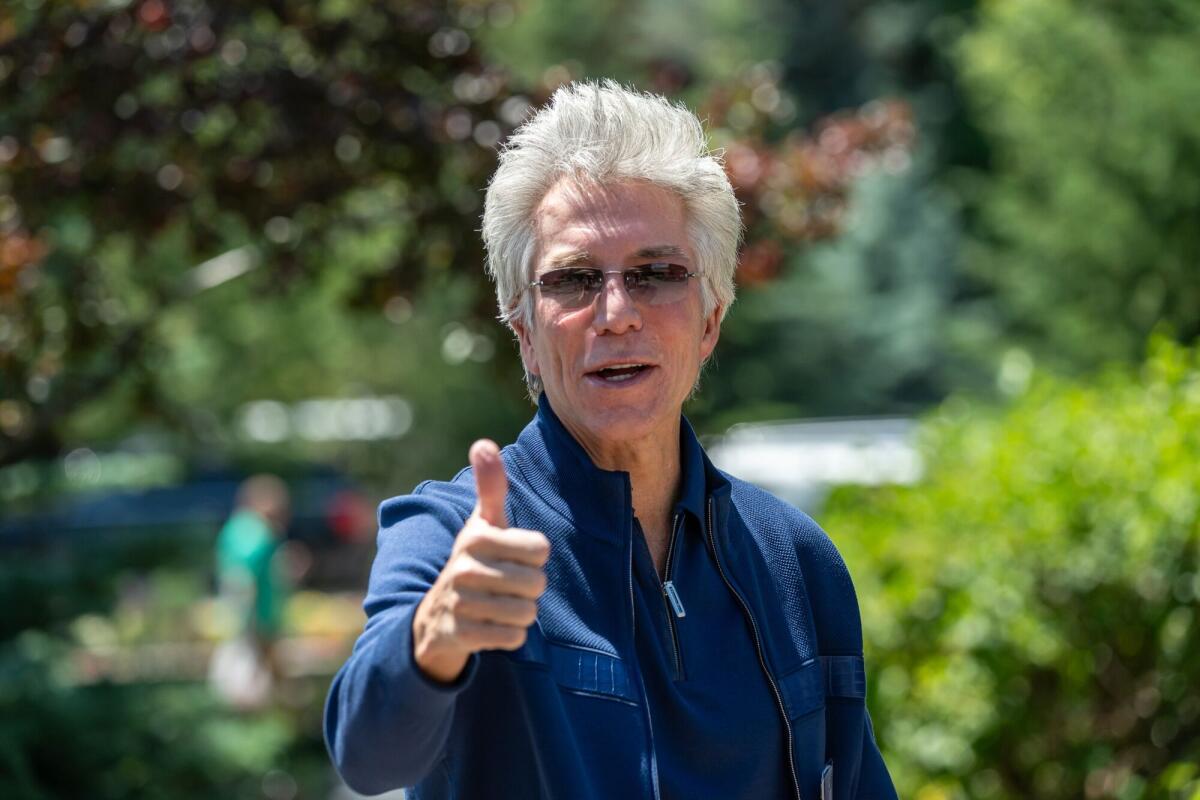 A man in a blue suit gives a thumbs up.