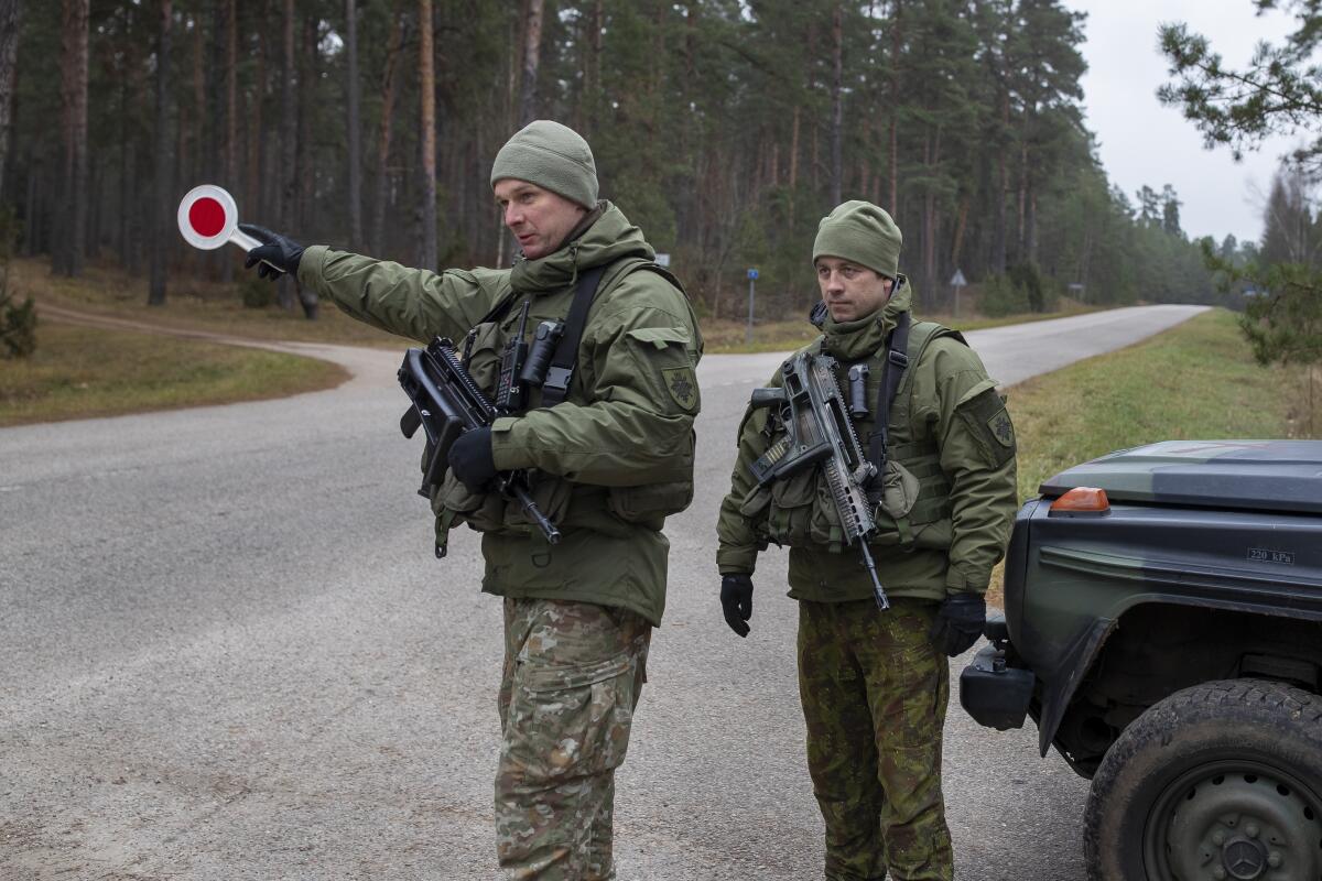 Lithuanian soldiers patrol a road near the Lithuania-Belarus border.