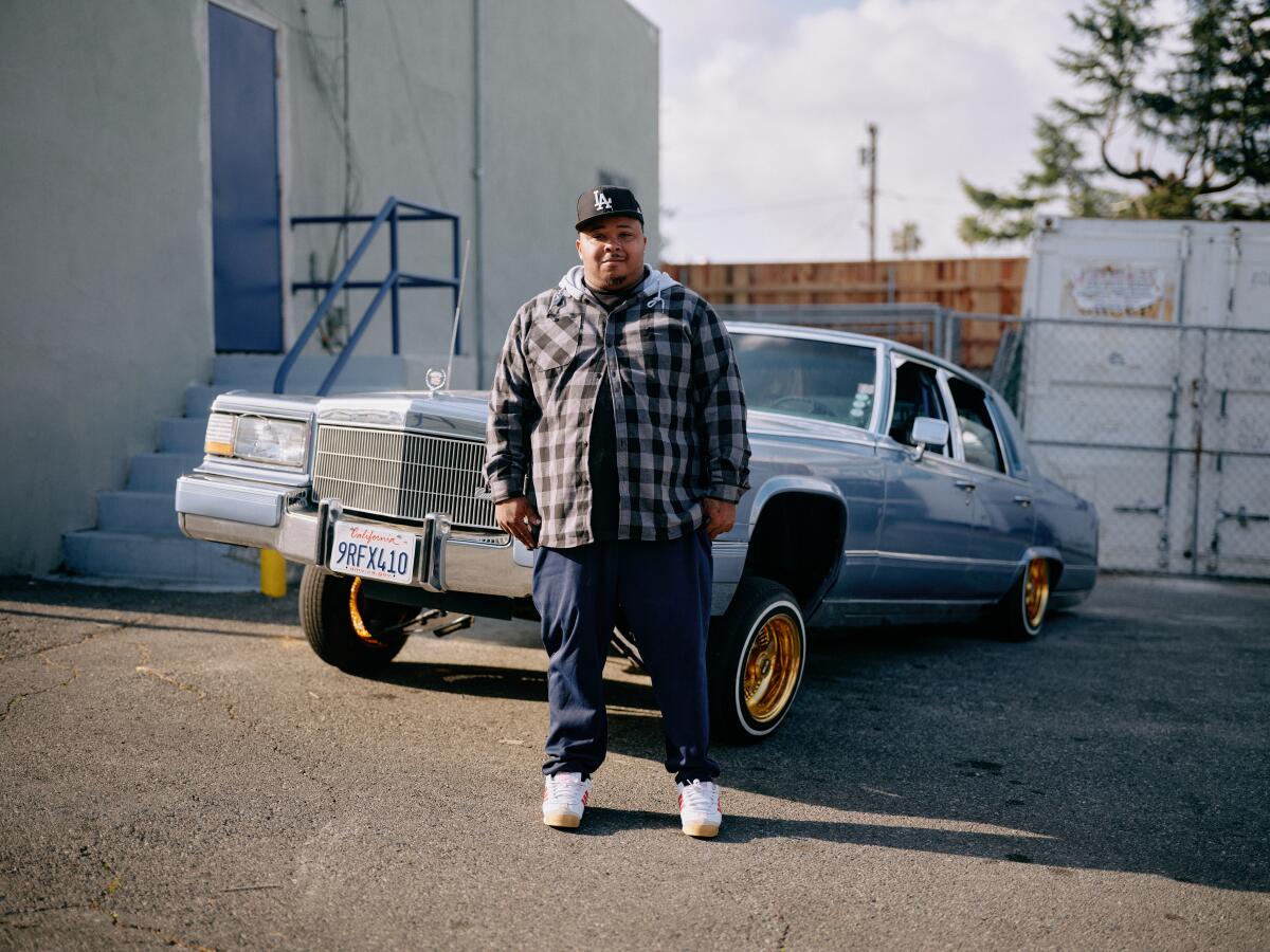 A man poses for a photo while standing in front of a car