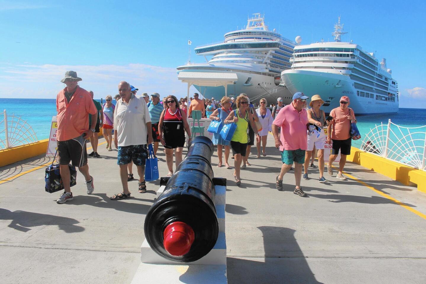 Passengers, many beach-bound and none discouraged by the cannon, disembark from Princess Cruises’ Crown Princess, left, and Silversea’s Silver Muse at Grand Turk, hit by hurricanes Irma and Maria last year.