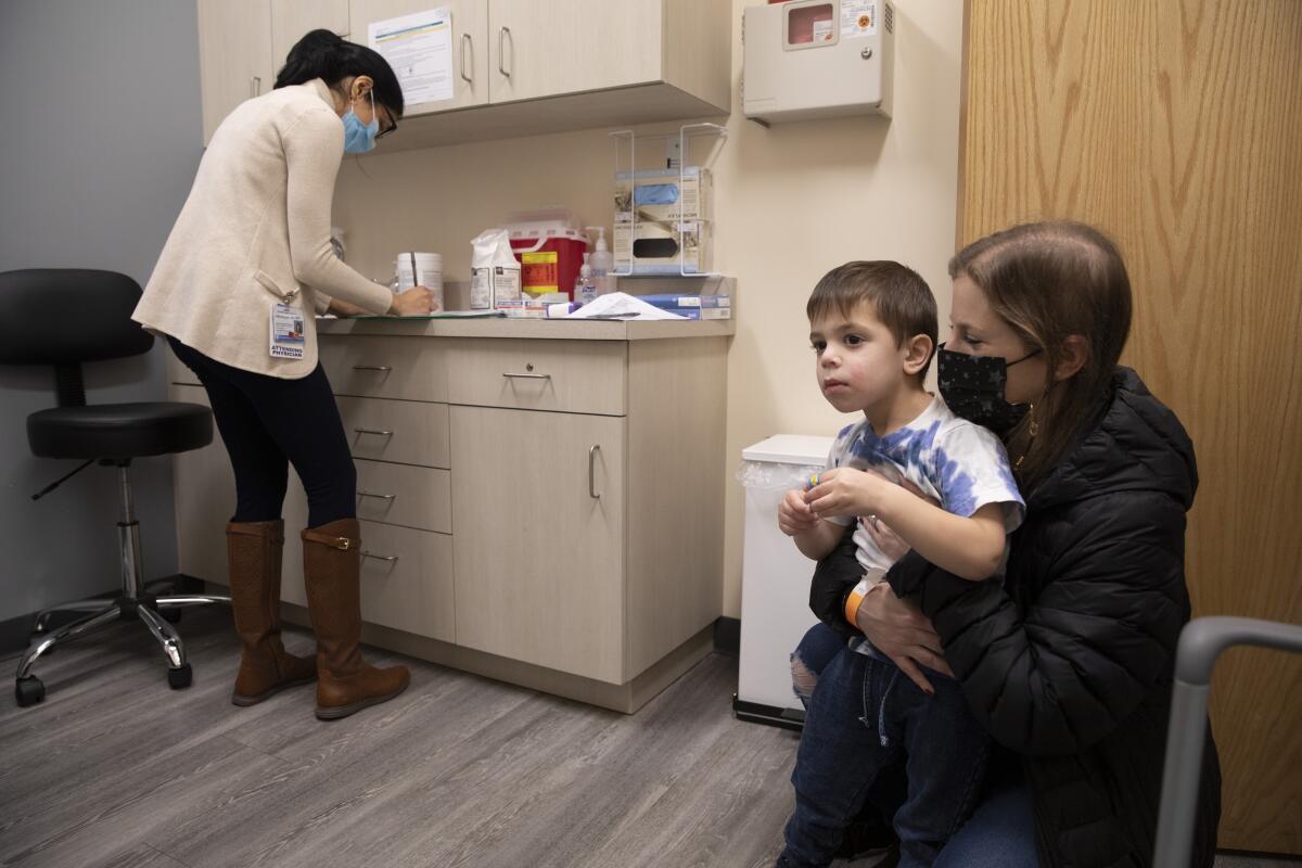 A woman holds her son in a medical office.