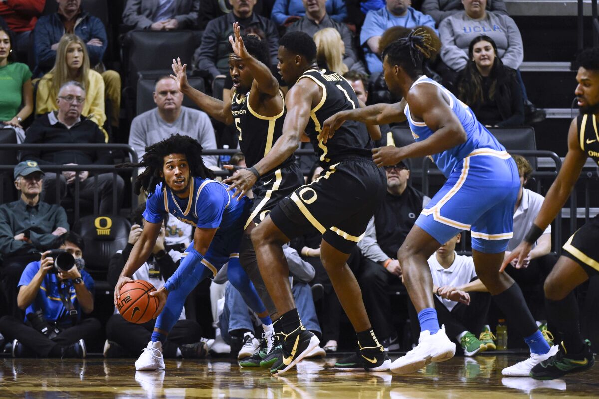 UCLA's Tyger Campbell looks to pass as he's double-teamed by Oregon's Jermaine Couisnard (5) and N'Faly Dante (1).