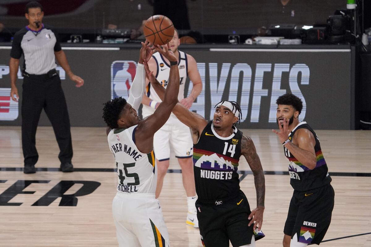 Utah's Donovan Mitchell attempts to shoot over Denver's Gary Harris.