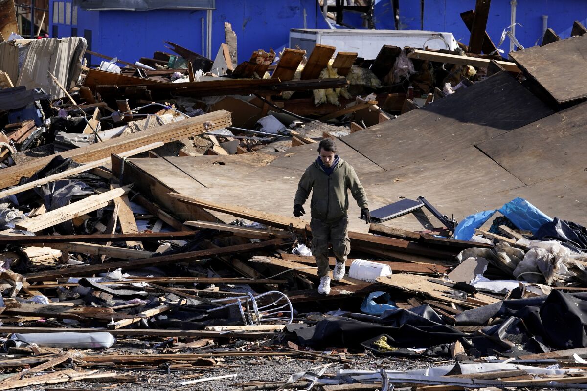 A man walks through debris and damage from a tornado 