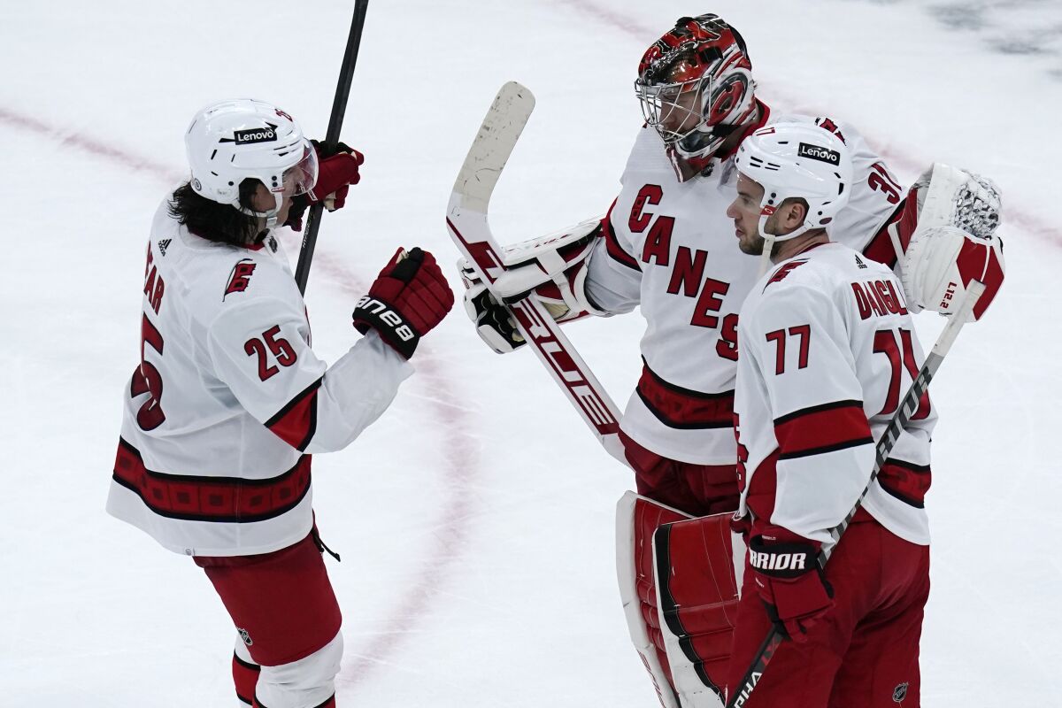 Carolina Hurricanes goaltender Frederik Andersen is congratulated by Ethan Bear (25) and Tony DeAngelo (77) after shutting out the Boston Bruins 6-0 in an NHL hockey game, Thursday, Feb. 10, 2022. (AP Photo/Charles Krupa)