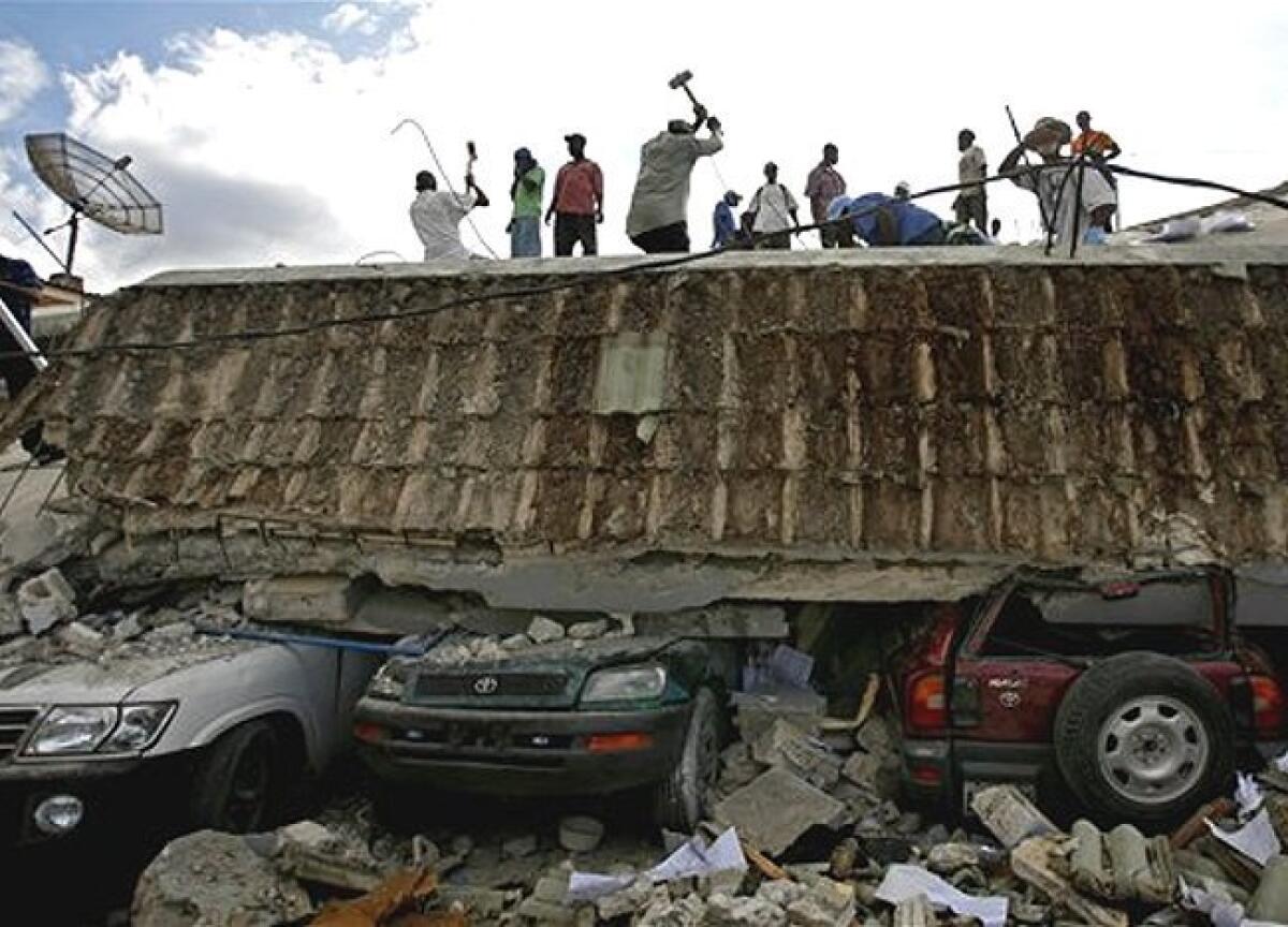 People search for survivors under the rubble of a collapsed building in Port-au-Prince, Haiti, Wednesday, Jan. 13, the day after an earthquake devastated Haiti's capital.