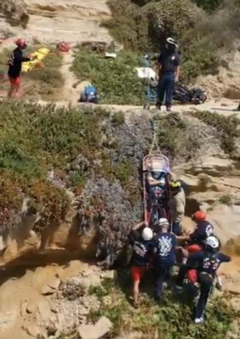 Lifeguards and firefighters hoist a fallen paraglider from a ravine at Black's Beach on July 12.