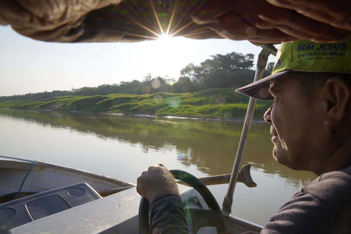 Jose Alves de Morais maneuvers a boat, in Carauari, Brazil, Thursday, Sept. 1, 2022. A Brazilian non-profit created a model for land ownership that welcomes both local people and scientists to collaborate in preserving the Amazon. "This is something that doesn't exist here in the Amazon, it doesn't exist anywhere in Brazil. If it works, which it will, it will attract a lot of people's attention," Morais, a resident, told The Associated Press. (AP Photo/Jorge Saenz)