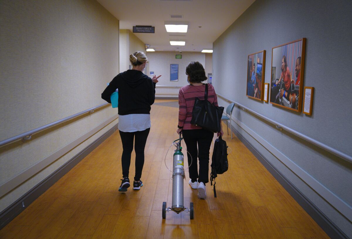 Carolina Nieto walks with respiratory therapist Suzanne Pruitt Friday, during her first visit to the COVID recovery clinic.