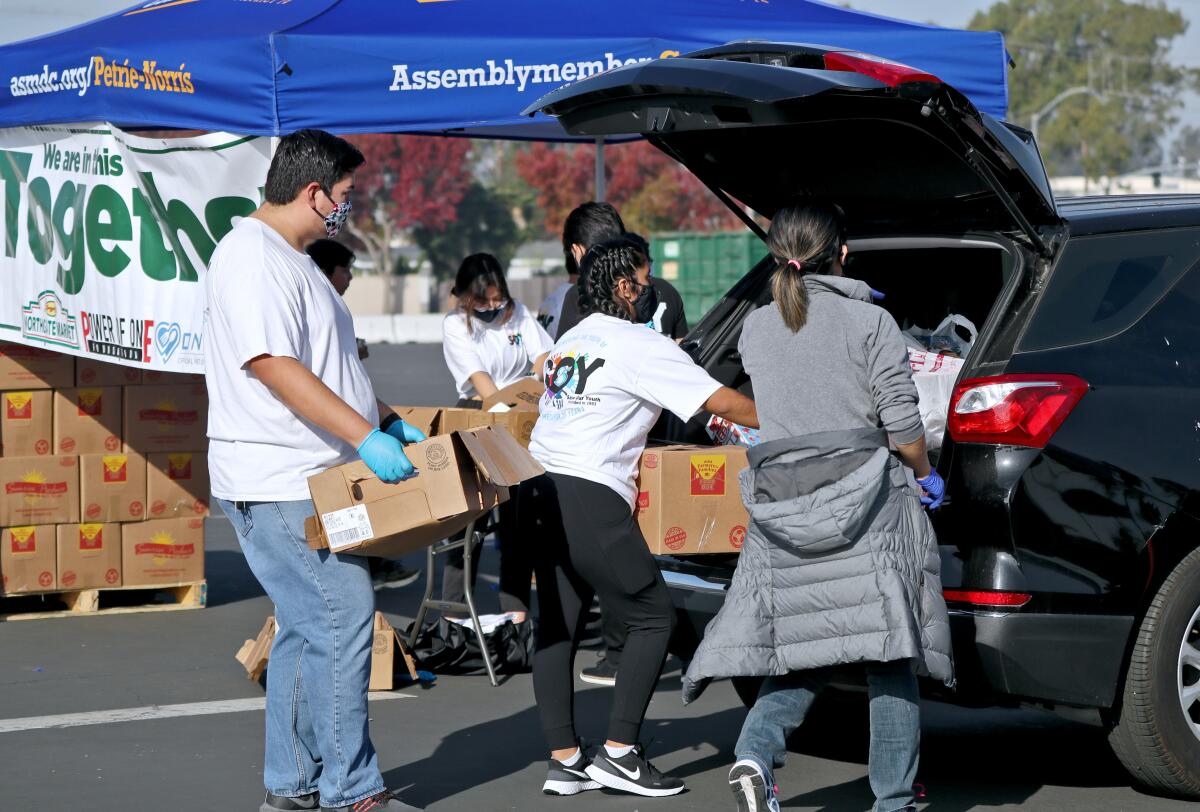 Volunteers help load boxes of food into vehicles at the Power of One Foundation Thanksgiving food giveaway on Saturday.