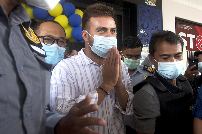 Russian citizen Sergei Kosenko is escorted out of an immigration office on the Indonesian resort island of Bali on Sunday.