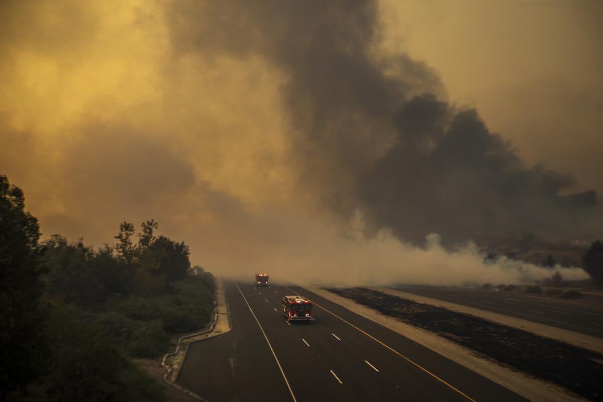 Firetrucks convoy through thick smoke on the 241 toll road to battle the advancing Silverado Fire fueled by Santa Ana winds