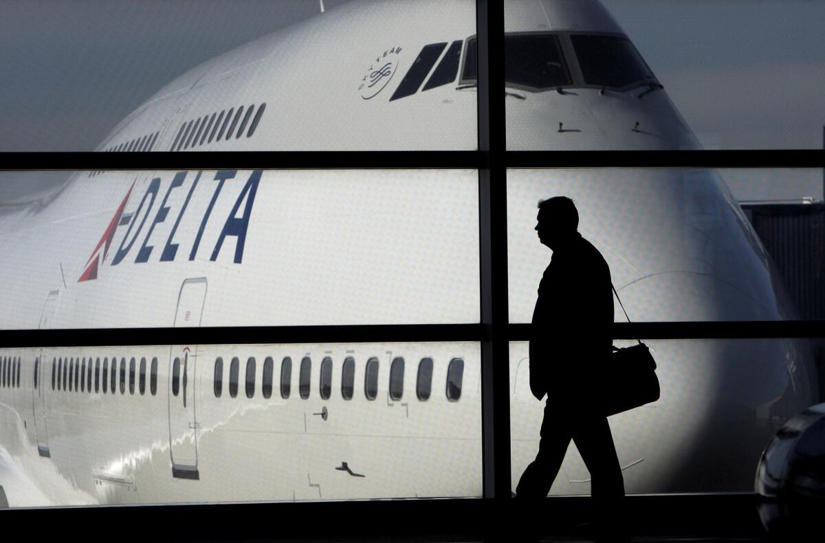 In this Jan. 21, 2010, file photo, a passenger walks past a Delta Airlines 747 aircraft in McNamara Terminal at Detroit Metropolitan Wayne County Airport in Romulus, Mich. The nation's top airlines reported $5.5 billion in net income for the three-month period that ended in June, the highest total since the same quarter in 2007.