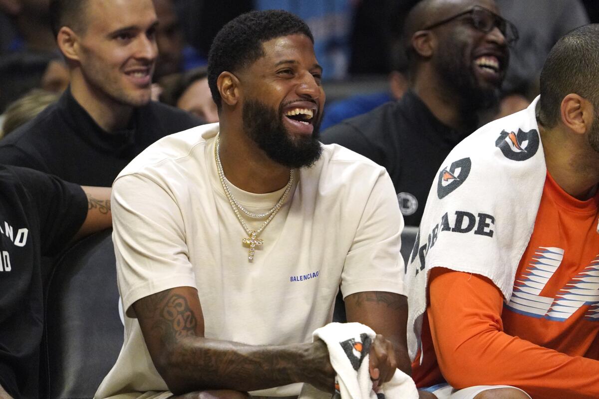 Clippers forward Paul George smiles as he sits on the bench.