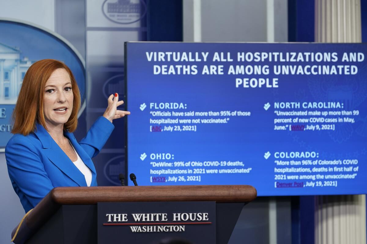 A person at a lectern points to a TV screen.