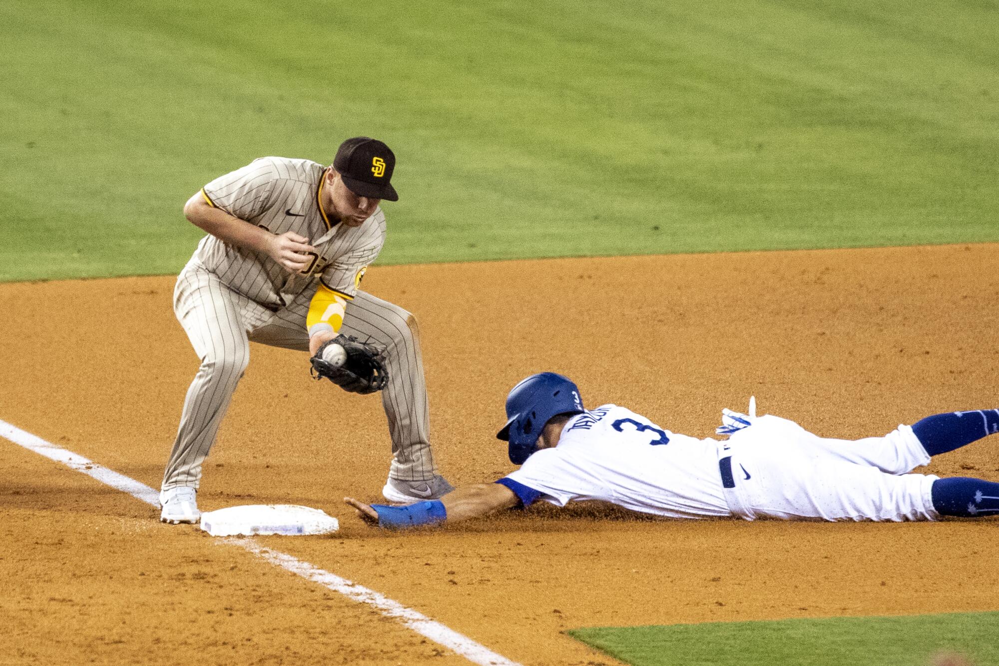 Dodgers baserunner Chris Taylor steals third base in front of San Diego Padres third baseman Brandon Drury.