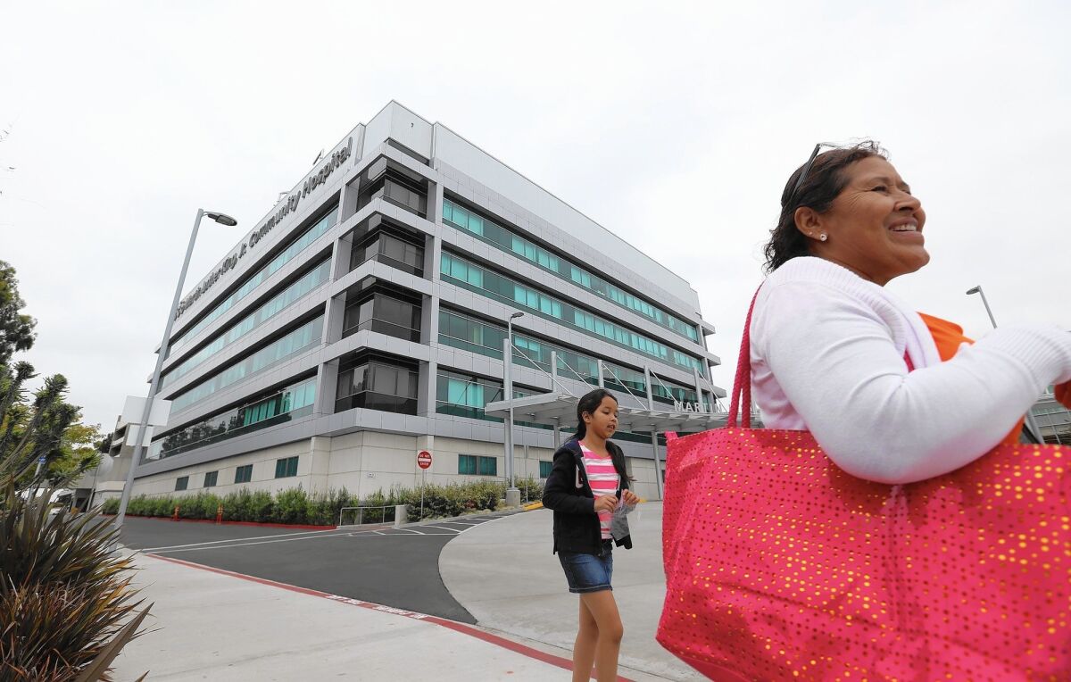 A woman and child walk in front of the new Martin Luther King Jr. Community Hospital.