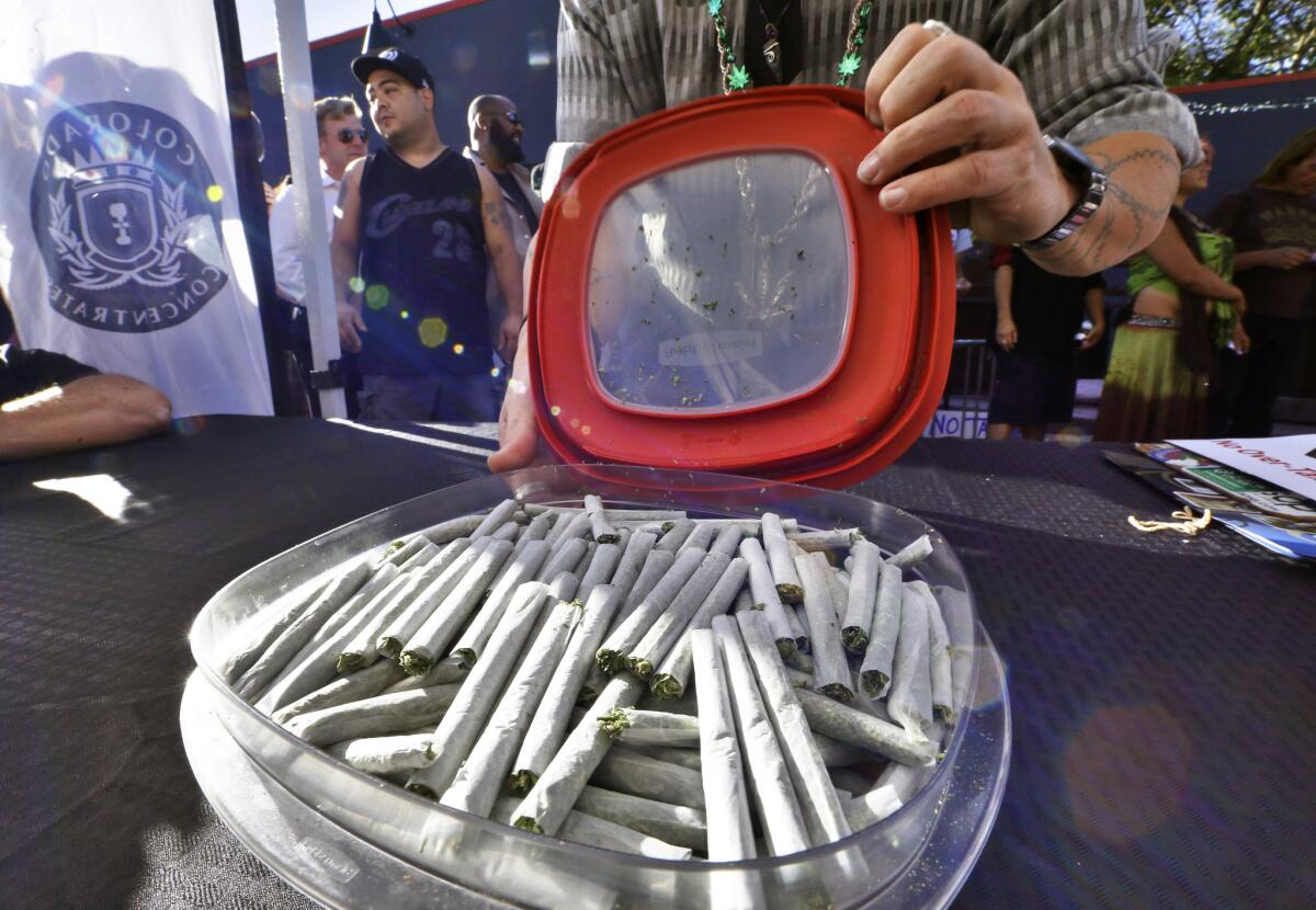 An activist prepares to hand out free marijuana joints at a rally in Denver criticizing Colorado's proposed 25% tax on recreational marijuana as too steep. The rally was held outside a pro pot-tax fundraiser attended by Gov. John Hickenlooper.