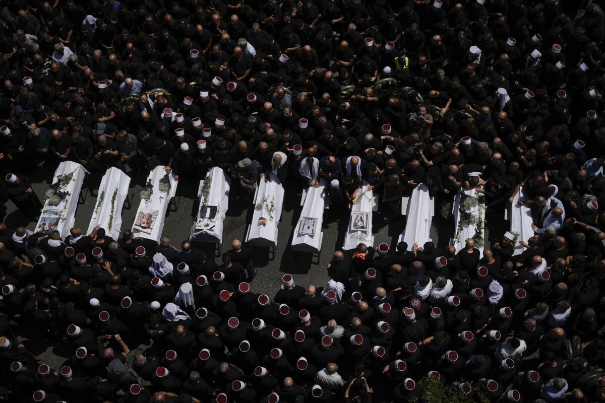 Dolientes de la minoría drusa rodean los cuerpos de algunos de los 12 niños y adolescentes