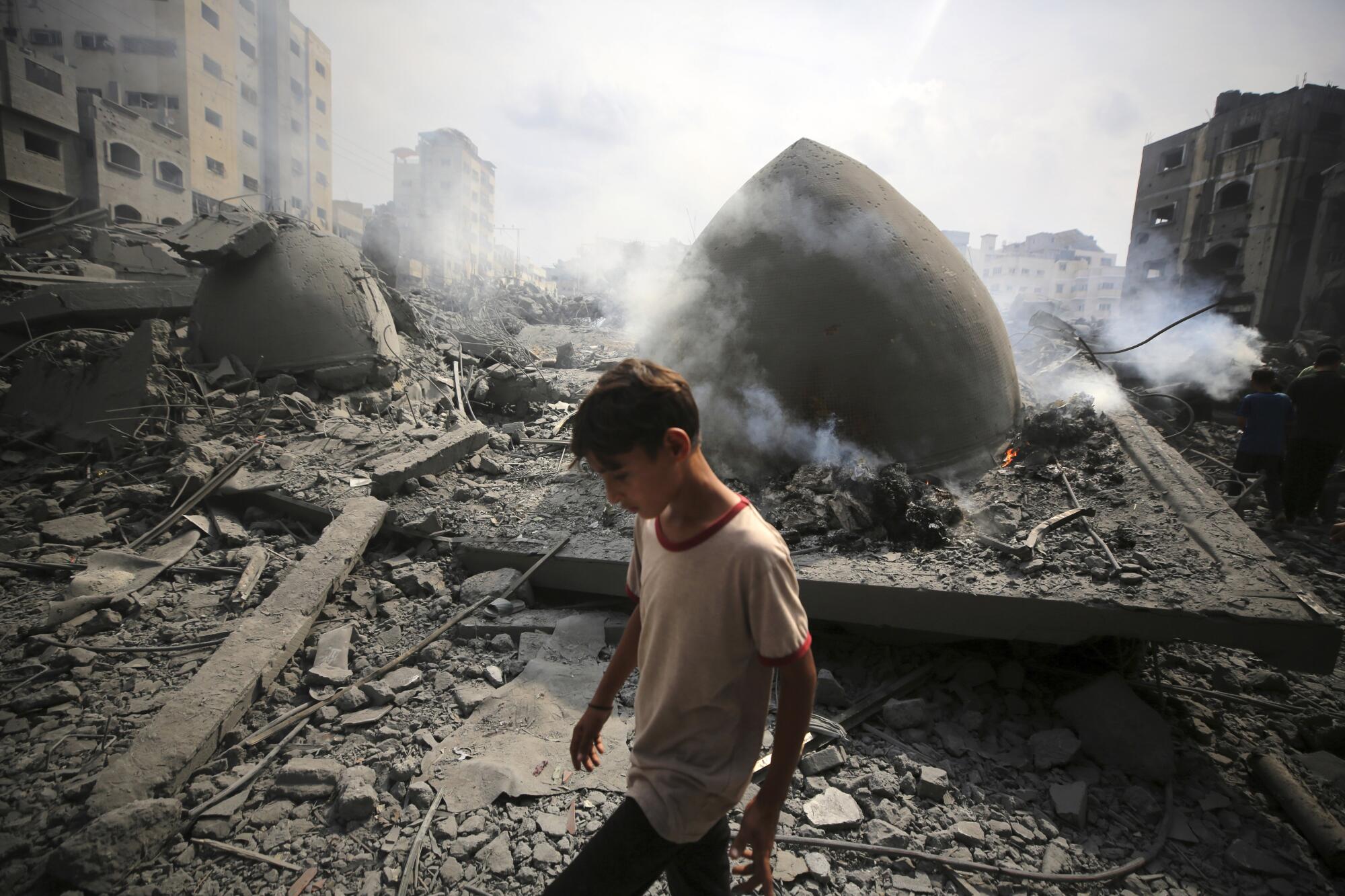 A person walks amid rubble and the smoking remains of a building 