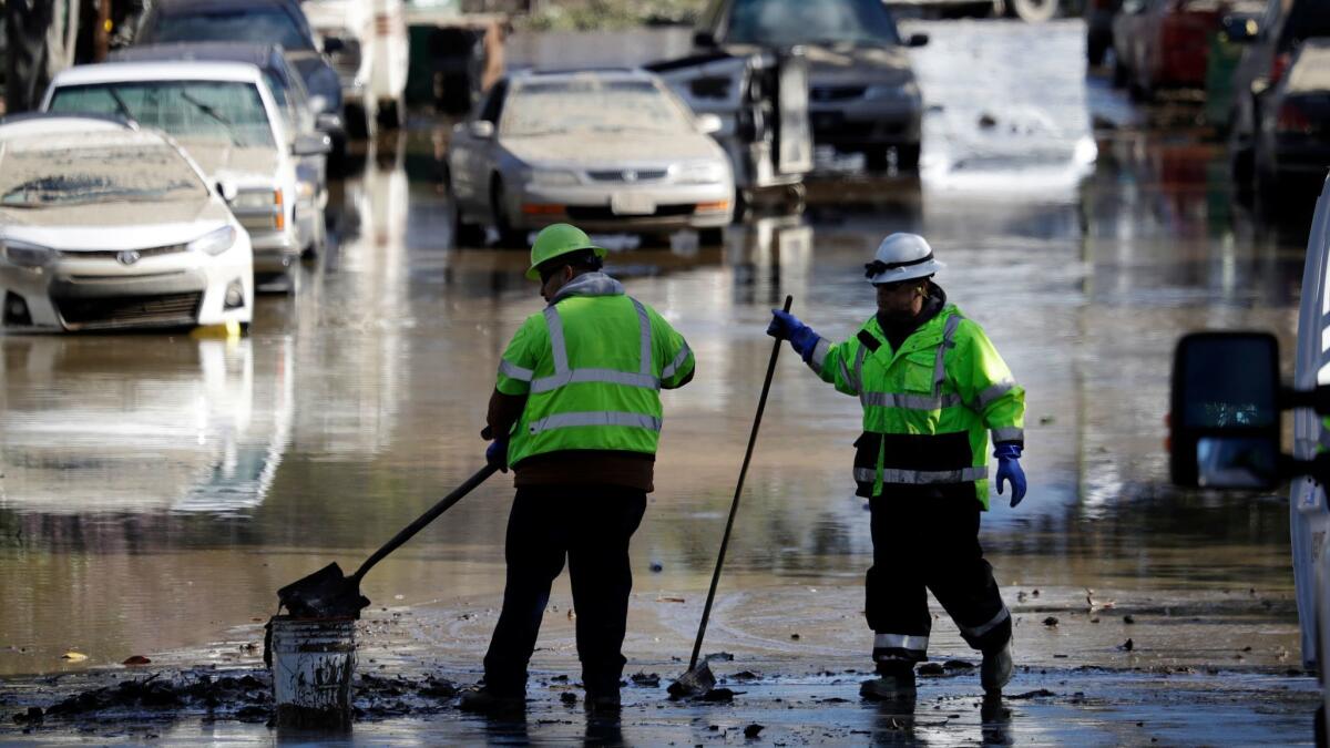 Crews shovel mud in a flooded San Jose street Feb. 23.