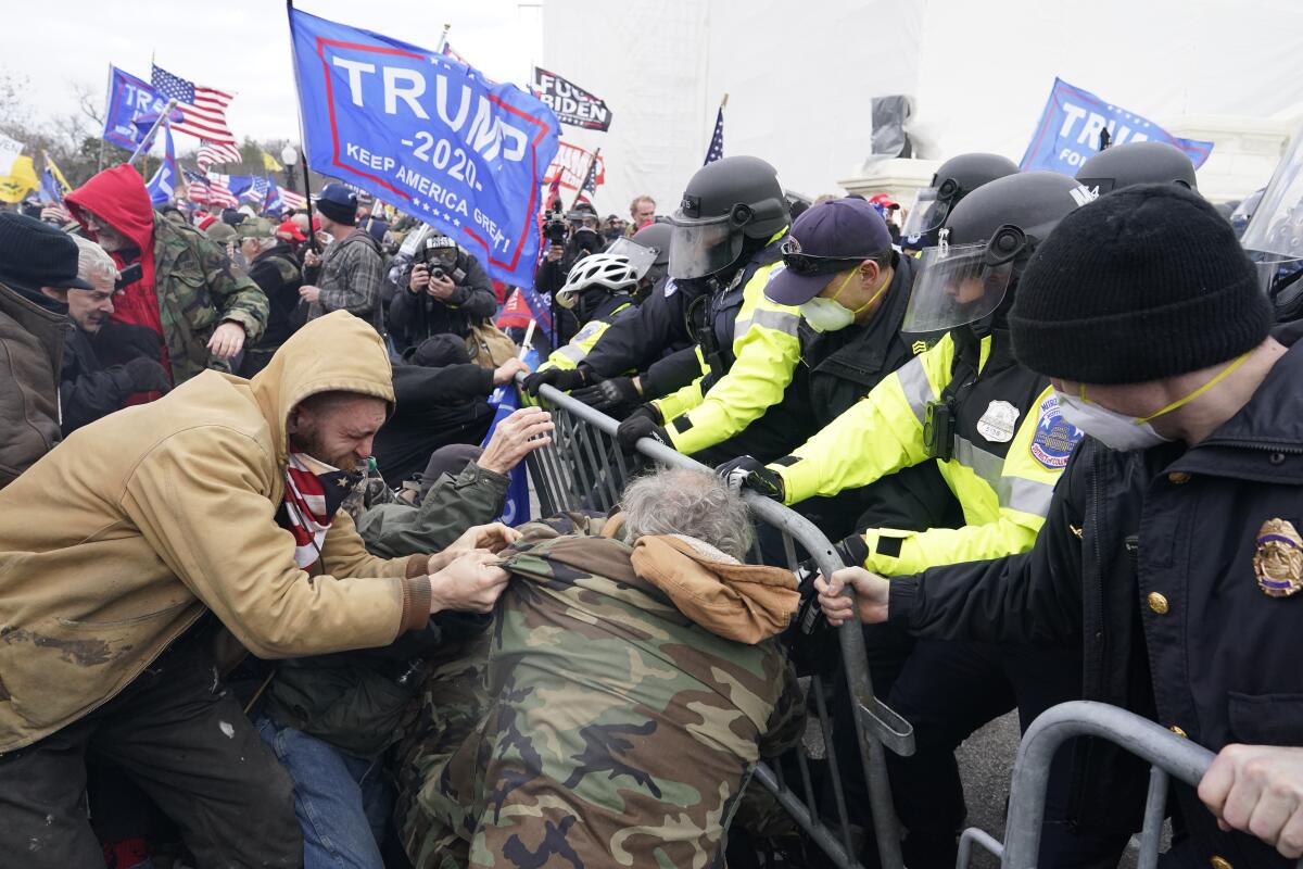 A mob of Trump supporters forces its way through a police barricade in front of the Capitol.