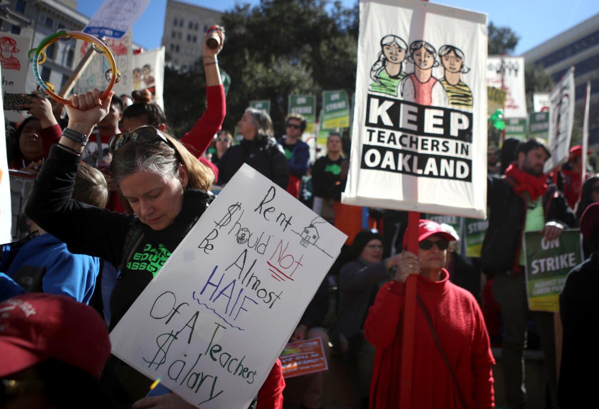 Students, teachers and parents carry signs as they march to the Oakland Unified School District headquarters.