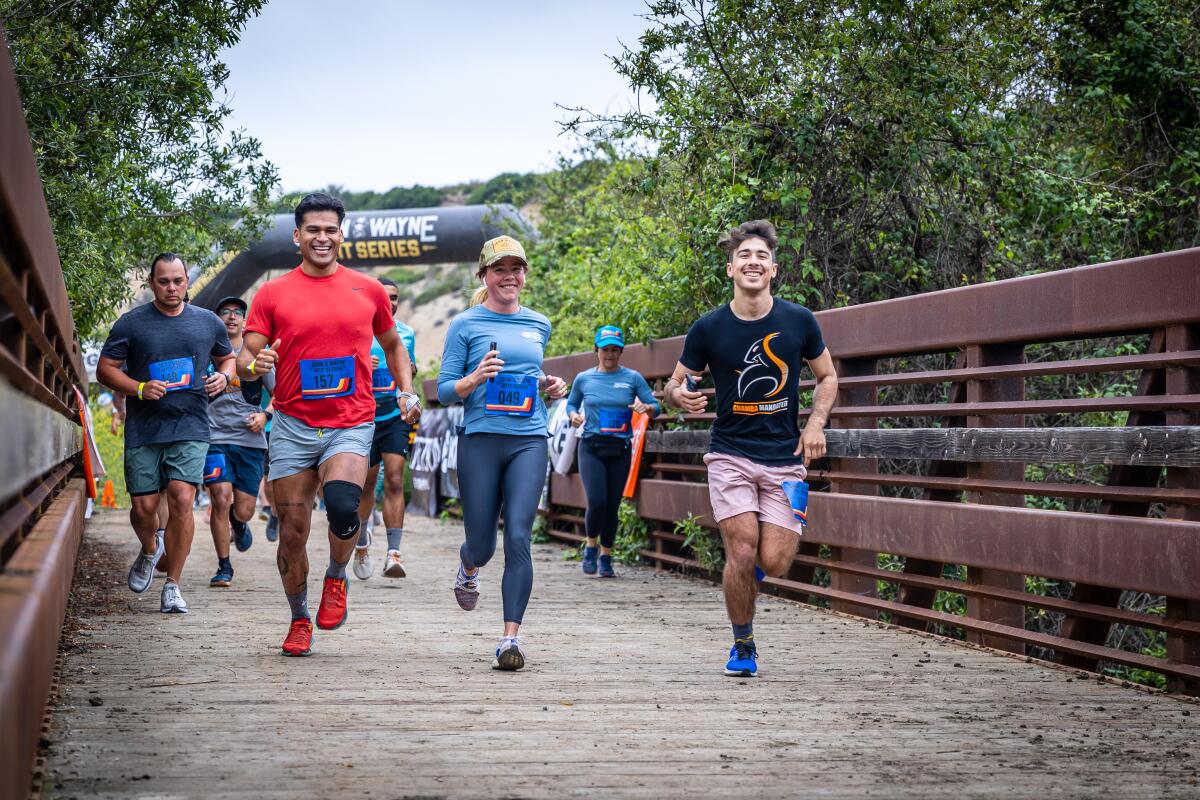 Runners race across the course through Crystal Cove State Park on Saturday as part of the 2023 John Wayne Grit Series.