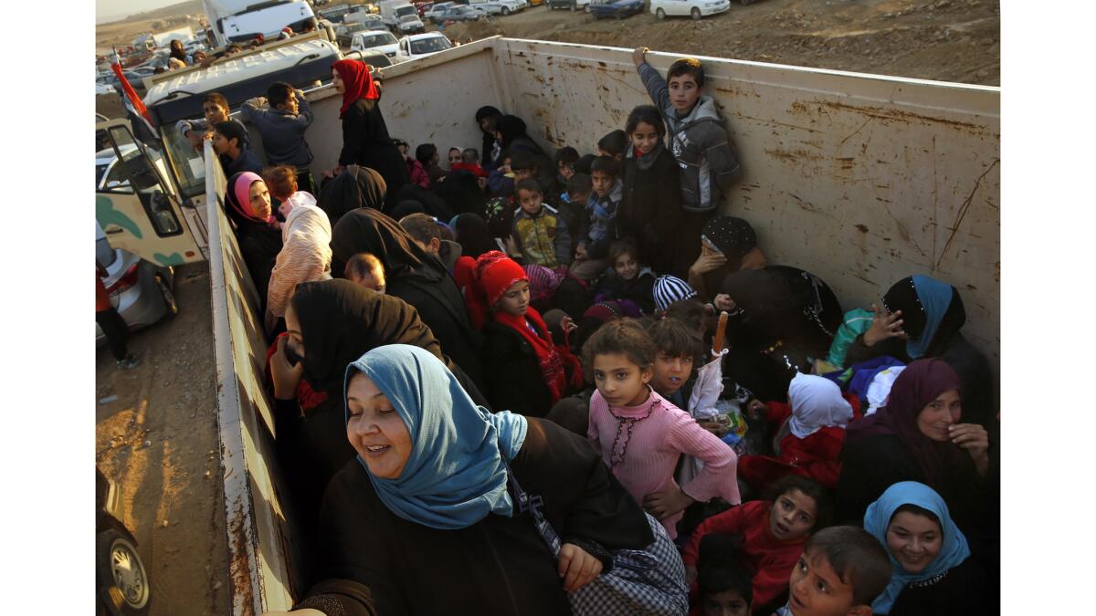 Thousands of men, women, and children fleeing violence in Mosul and surrounding villages arrive by dump trucks and buses at UNHCR Camp Hassansham.